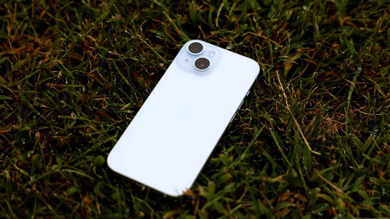 iPhone 15 de color azul sobre suelo de hierba