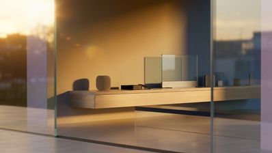 Dispositivos Apple Home sobre un mueble de madera minimalista vistos a través de un ventanal al atardecer.