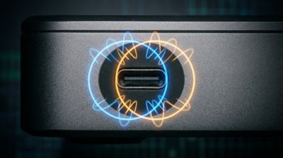 Primer plano de un puerto USB-C en el chasis de un Mac mini con una ilustración superpuesta de ondas de frecuencia entrelazadas en colores azul y naranja.