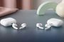 Dos pares de auriculares inalámbricos blancos con sus respectivos estuches de carga sobre una superficie gris.