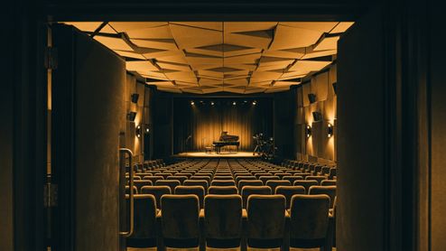 Vista desde la puerta del patio de butacas hacia el escenario con un piano de cola en el Apple Music Hall.
