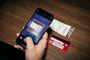 Un iPhone enfoca con su cámara un billete de papel sobre una mesa de madera para escanear su código de barras en Apple Wallet.