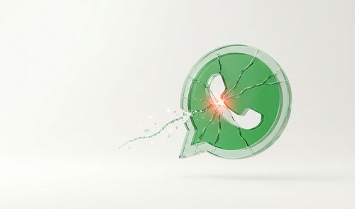 Icono tridimensional de WhatsApp fabricado en cristal verde con grietas y una fractura central que desprende destellos sobre fondo blanco.