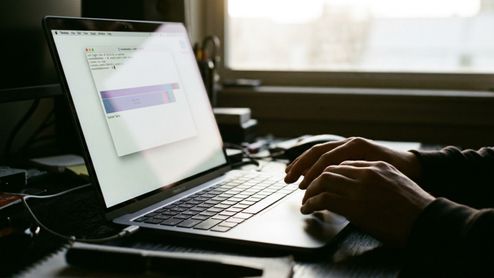Primer plano de unas manos usando el teclado de un MacBook Pro que muestra una ventana de terminal y gráficos de almacenamiento en pantalla.
