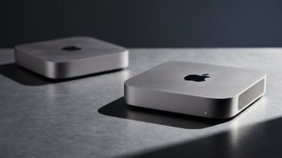 Dos ordenadores Mac mini de color plata situados sobre una superficie metálica bajo una iluminación lateral.