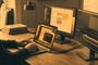 Persona trabajando con un MacBook conectado a dos monitores externos que muestran diferentes aplicaciones de gestión y edición.