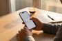 Manos de una persona sosteniendo un iPhone 18 Pro que muestra el menú de ajustes en la pantalla sobre una mesa de madera