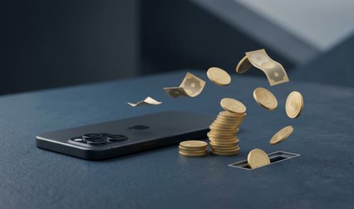 Monedas y billetes volando desde una ranura en una superficie hacia un teléfono iPhone de color oscuro.