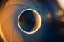 Primer plano de las láminas de un diafragma de cámara fotográfica formando una apertura circular iluminada.