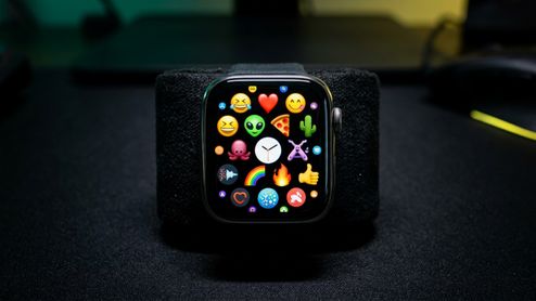 Primer plano de un Apple Watch mostrando una cuadrícula de emojis variados en su pantalla.