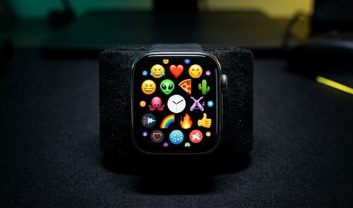 Primer plano de un Apple Watch mostrando una cuadrícula de emojis variados en su pantalla.