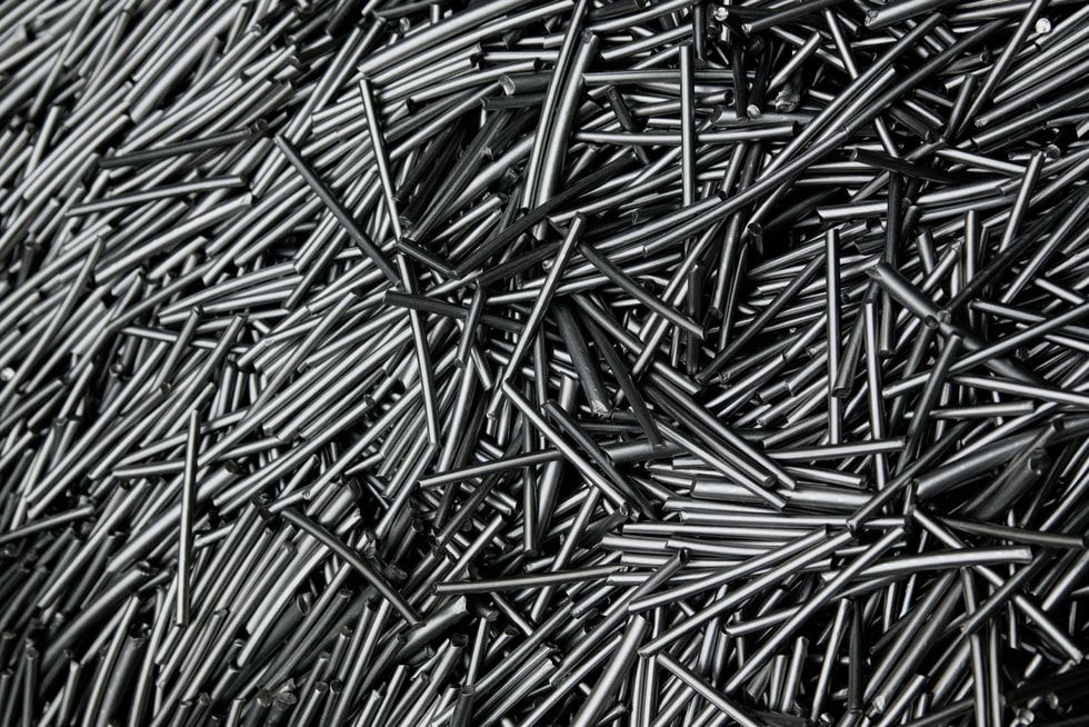 Primer plano de una gran cantidad de barras de metal apiladas de forma desordenada.