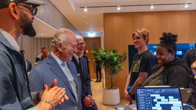 El rey Carlos III y Tim Cook conversan con jóvenes participantes de los Creative Labs frente a un iPad con software de edición musical.