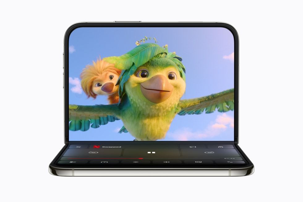 Interfaz de la aplicación Netflix en un iPhone Duo plegado en ángulo de noventa grados, mostrando una película de animación en la mitad superior y controles de reproducción en la inferior.