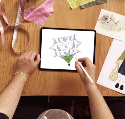 Bünyamin Aydın dibujando el boceto de un globo aerostático en un iPad Pro M5 con el Apple Pencil Pro sobre una mesa de diseño textil.