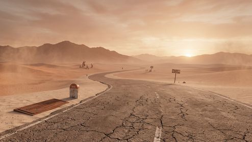 Carretera agrietada y sinuosa que atraviesa un desierto de arena bajo un cielo anaranjado al atardecer.