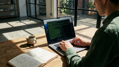 Persona utilizando la aplicación Terminal en un ordenador portátil Mac para ejecutar líneas de código en un entorno de oficina iluminado.
