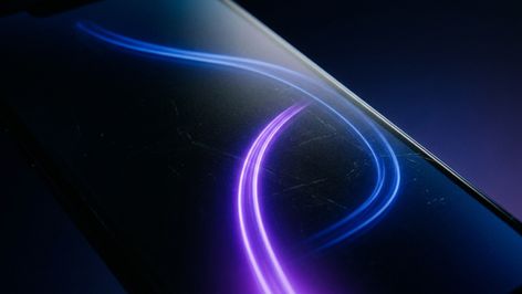 Plano detalle de la pantalla de un smartphone con una estela de luz azul y violeta en forma de onda.
