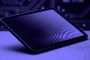 Tableta iPad mini situada en ángulo sobre una superficie con fondo de circuitos, bajo una iluminación de tonos violetas.