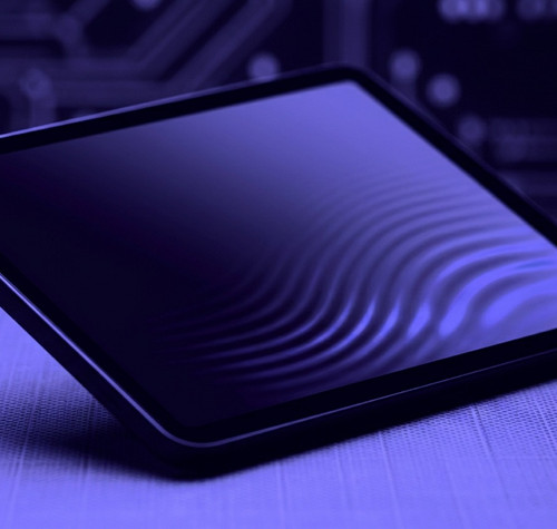 Tableta iPad mini situada en ángulo sobre una superficie con fondo de circuitos, bajo una iluminación de tonos violetas.