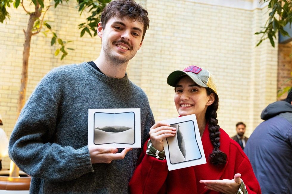 Dos personas sonríen mientras sujetan cajas del iPhone Duo en el interior de una tienda.