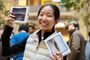 Una mujer sonríe en una Apple Store mientras sostiene dos cajas del iPhone Duo plegable.