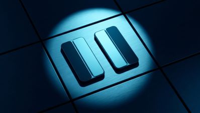 Icono metálico de pausa iluminado por un foco sobre una superficie cuadriculada azul.