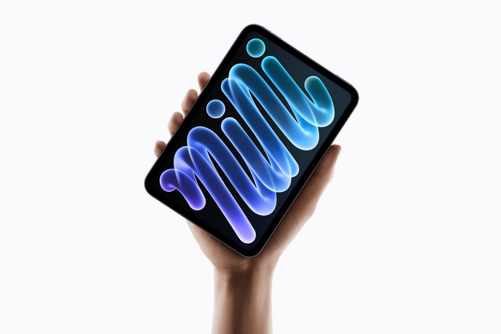 Una mano sujeta en vertical un iPad mini con pantalla OLED de 8,5 pulgadas sobre un fondo blanco.