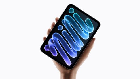 Mano sosteniendo en vertical un iPad mini que muestra un fondo de pantalla con formas abstractas en tonos azules y violetas.