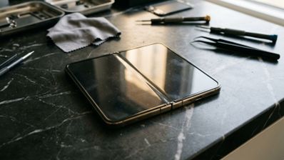iPhone Duo abierto sobre una mesa de trabajo rodeado de herramientas de precisión y pinzas.