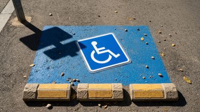 Símbolo internacional de accesibilidad pintado sobre una plaza de aparcamiento reservada en la vía pública.